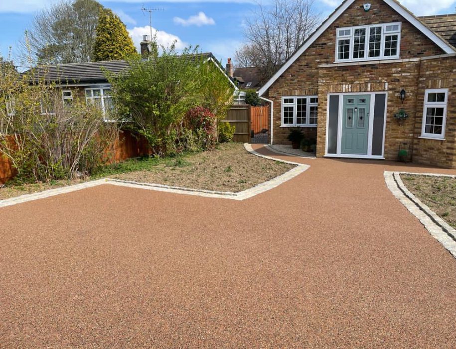 Terracotta and gold resin bound driveway at a brick and flint house