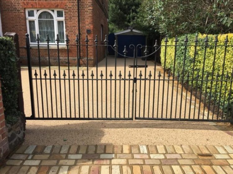 Resin driveway behind iron gates with a sandstone apron